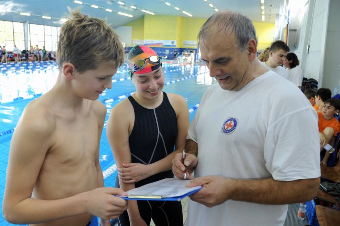 Mannschaftsleiter steht mit zwei Schwimmern am Beckenrand in der Schwimmhalle des Sportforums Chemnitz