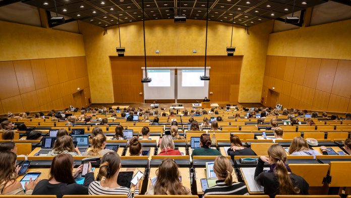 Mehrere Personen sitzen in einem Hötrsaal.